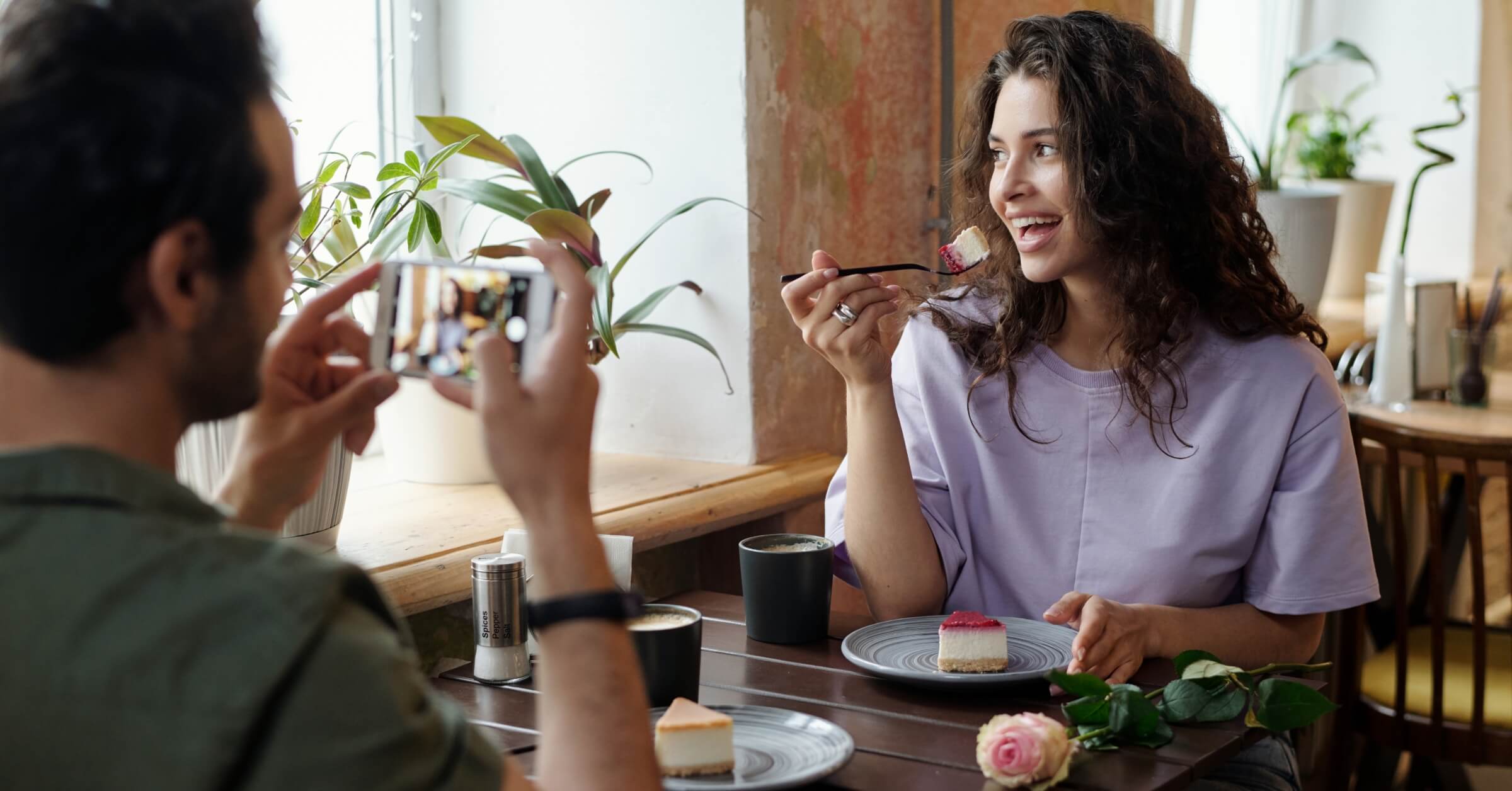 Ung mann tar bilde av ung jente som spiser kake