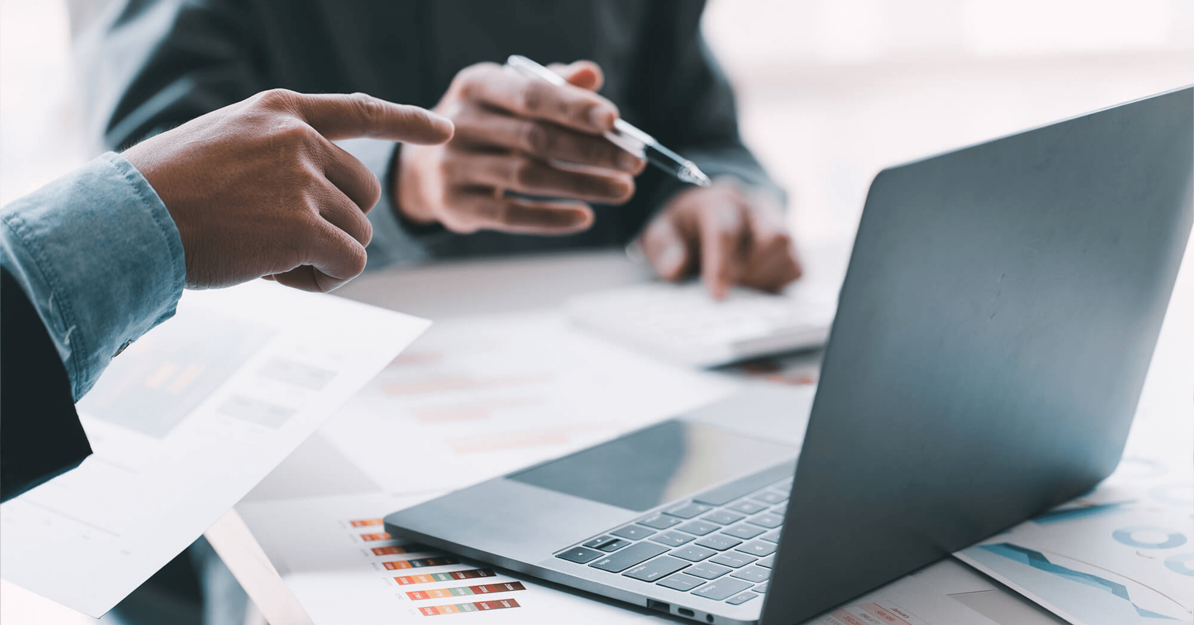 To personer samarbeider om noe på en dataskjerm. Den ene peker på skjermen, den andre har en penn i hånden.